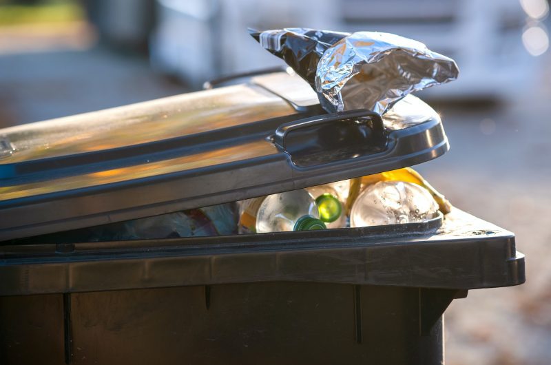 Closeup of trash can container full of garbage.