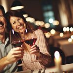 Un couple heureux trinquant avec des verres de vin lors d'un dîner romantique.