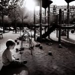 Un enfant assis seul dans une cour de récréation.