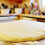 Une pâte à pizza maison parfaitement étalée sur une table de cuisine, prête à être garnie.