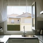 Une cuisine propre avec une fenêtre ouverte équipée d'une moustiquaire.
